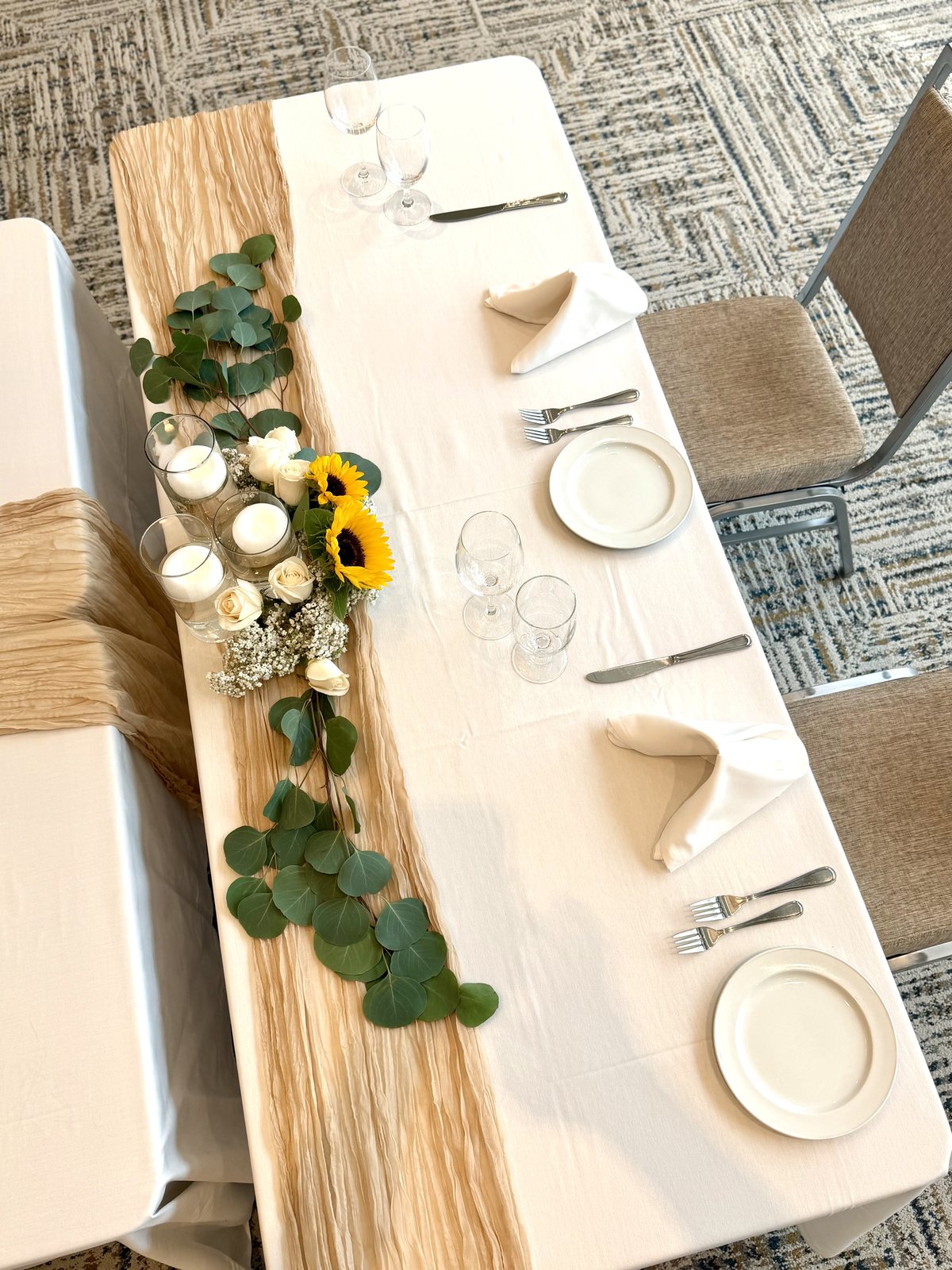 Wedding reception place settings with sunflowers, white roses and eucalyptus along a natural runner — Four Points by Sheraton Kelowna