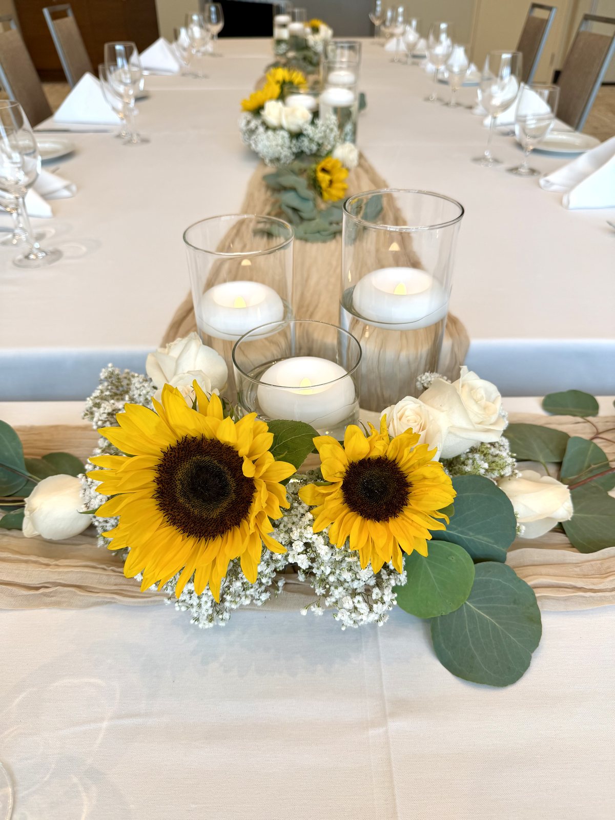 Wedding reception table with sunflower centrepieces, white roses, floating candles and a natural runner at the Four Points by Sheraton Kelowna Airport