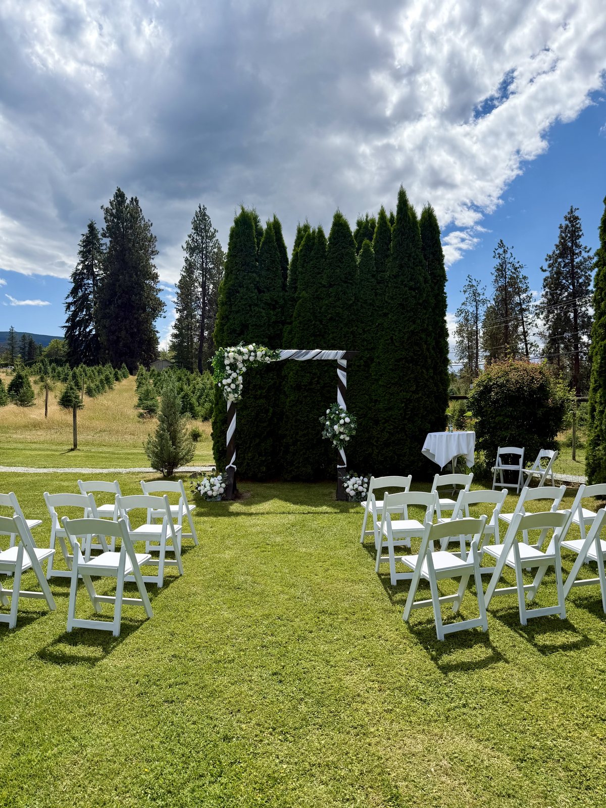 Outdoor wedding ceremony with white chairs, an aisle and a styled arch at Meadow Vista Honey Wines, Kelowna